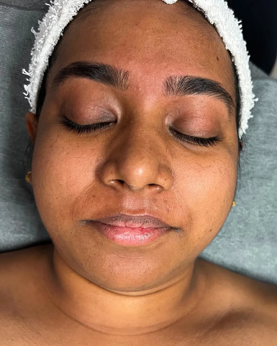 Real client lying back in a headband, eyes closed, eyebrows freshly threaded, before her facial at Shubh Beauty